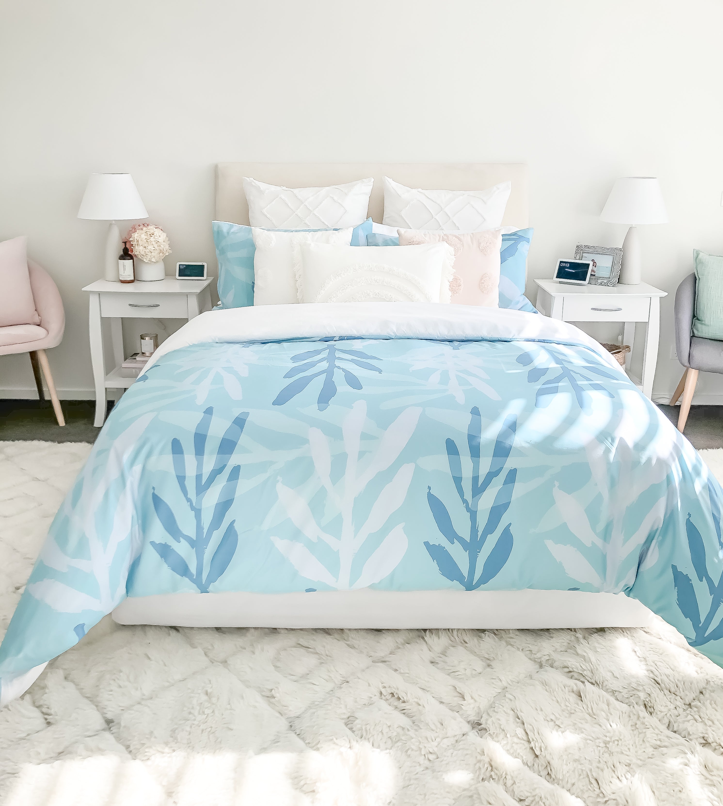 A light filled bedroom with the Botanica quilt cover in Blue on a queen sized bed. There are complimenting display pillows in mix of soft pastel colours.