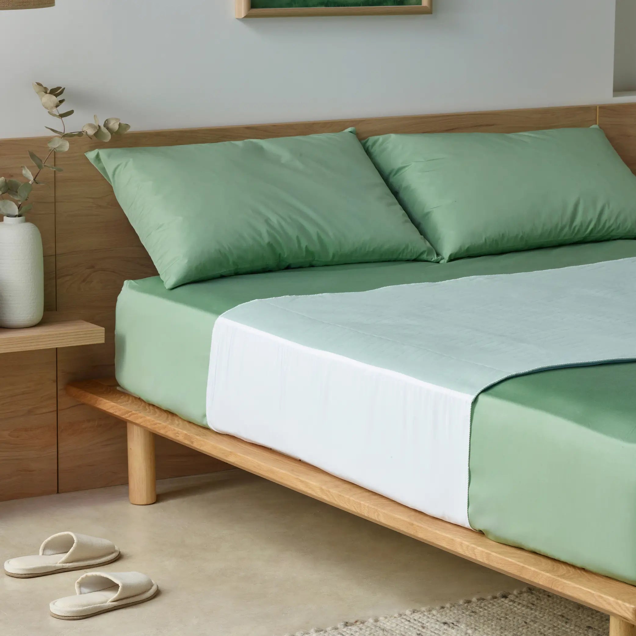 Boss Waterproof Bed Pad on a stylish bed with sage green sheets. Designed for superior incontinence protection, this washable, reusable bed pad keeps mattresses dry while providing a soft, breathable, and comfortable sleep surface.
