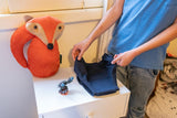 Little boy holding navy toilet training briefs on a small white table.  On the table there is also a toy fox and a figurine.