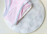 Pink briefs laying down a a peal background