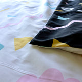 Bright colourful quilt cover fabric.  One side has a whirw background, the other a black background.  Both with colourful shapes.