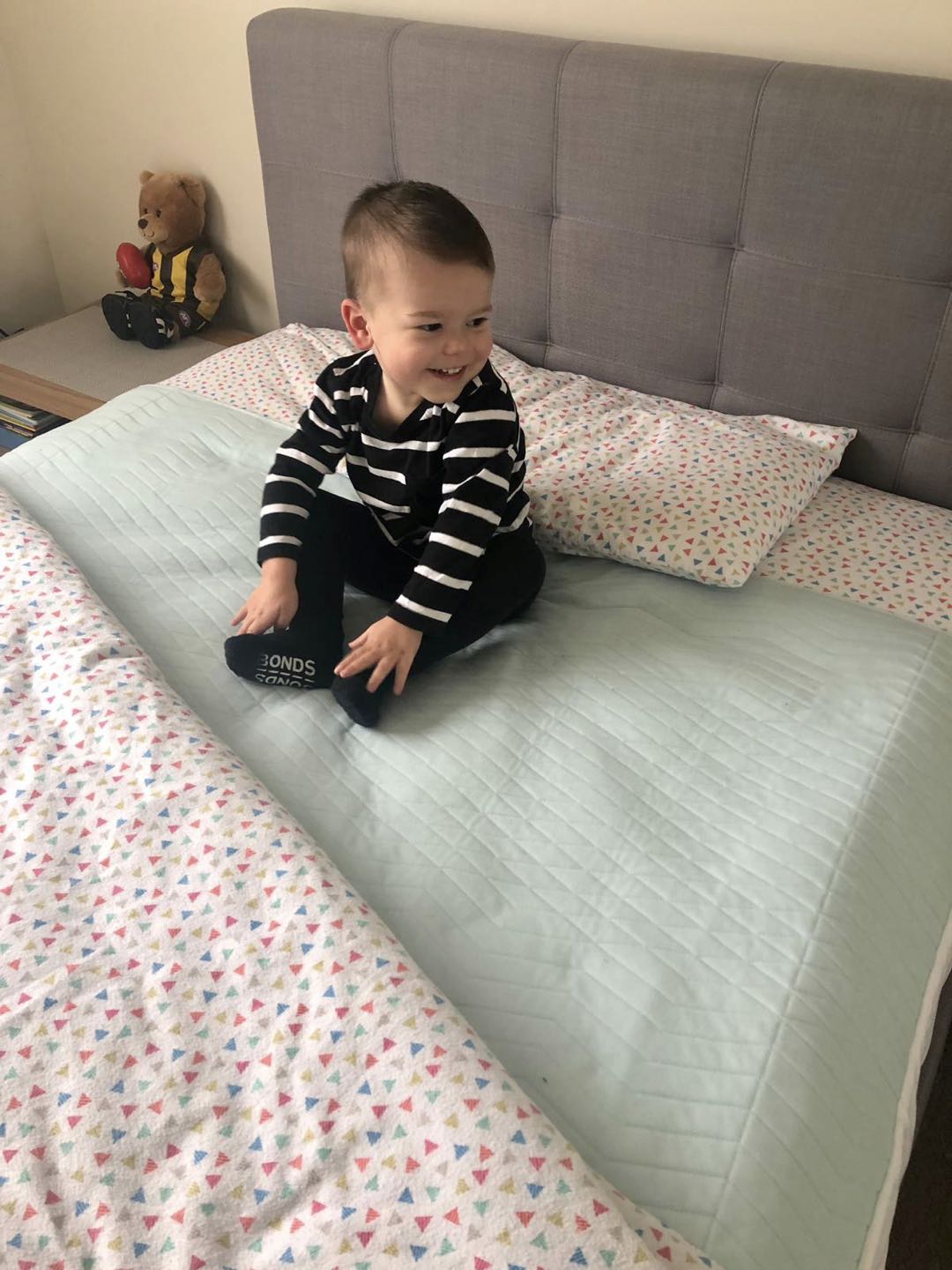 Little boy sitting on top of a aqua bed pad.