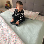 Little boy sitting on top of a aqua bed pad.
