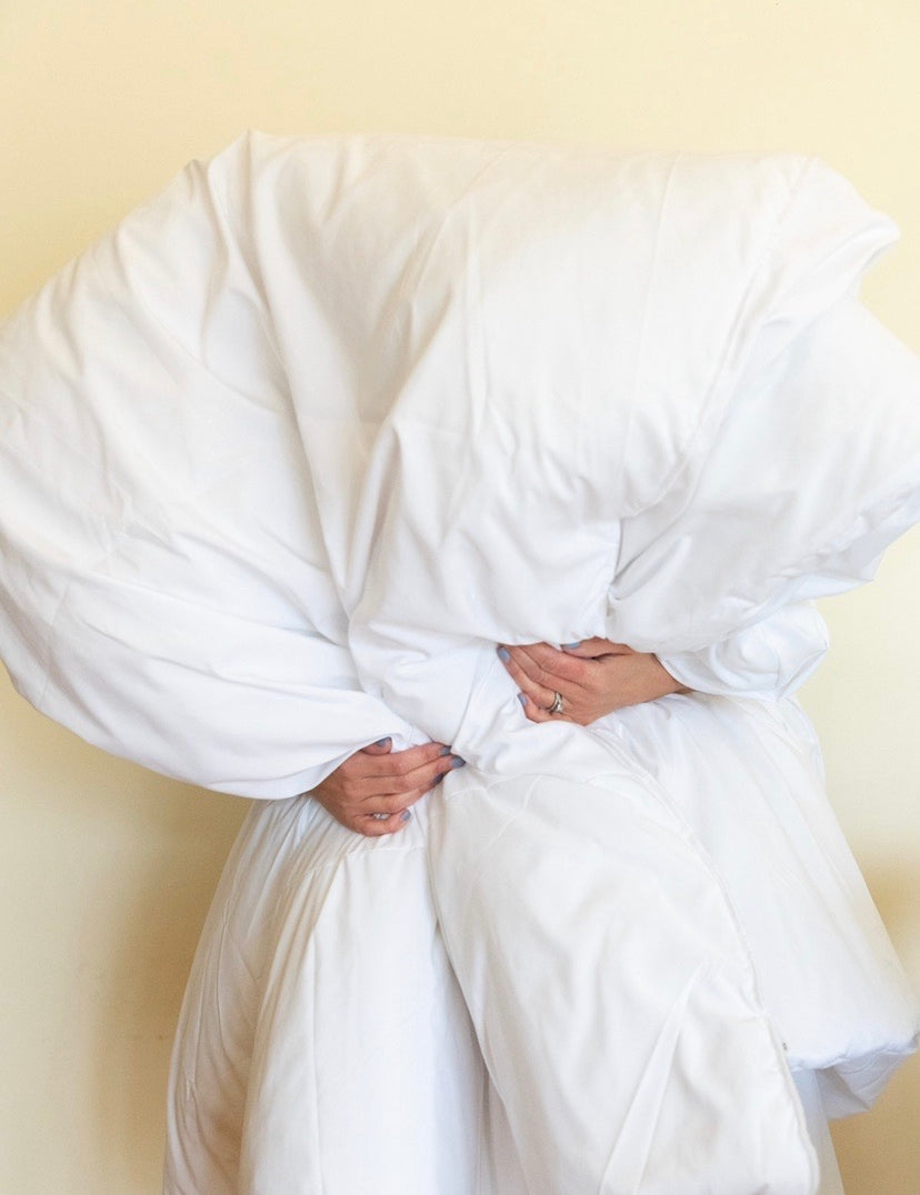 A person hold a big, fluffy white quilt.
