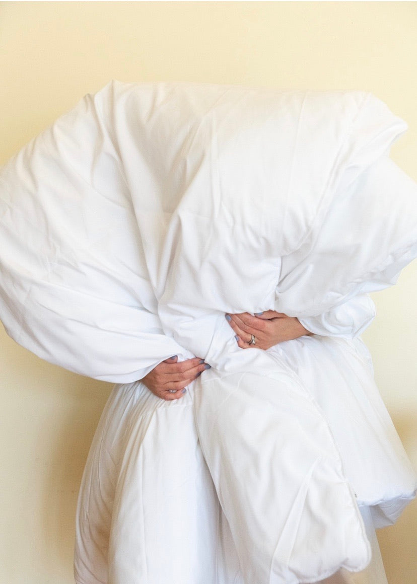 A person hold a big, fluffy white quilt.